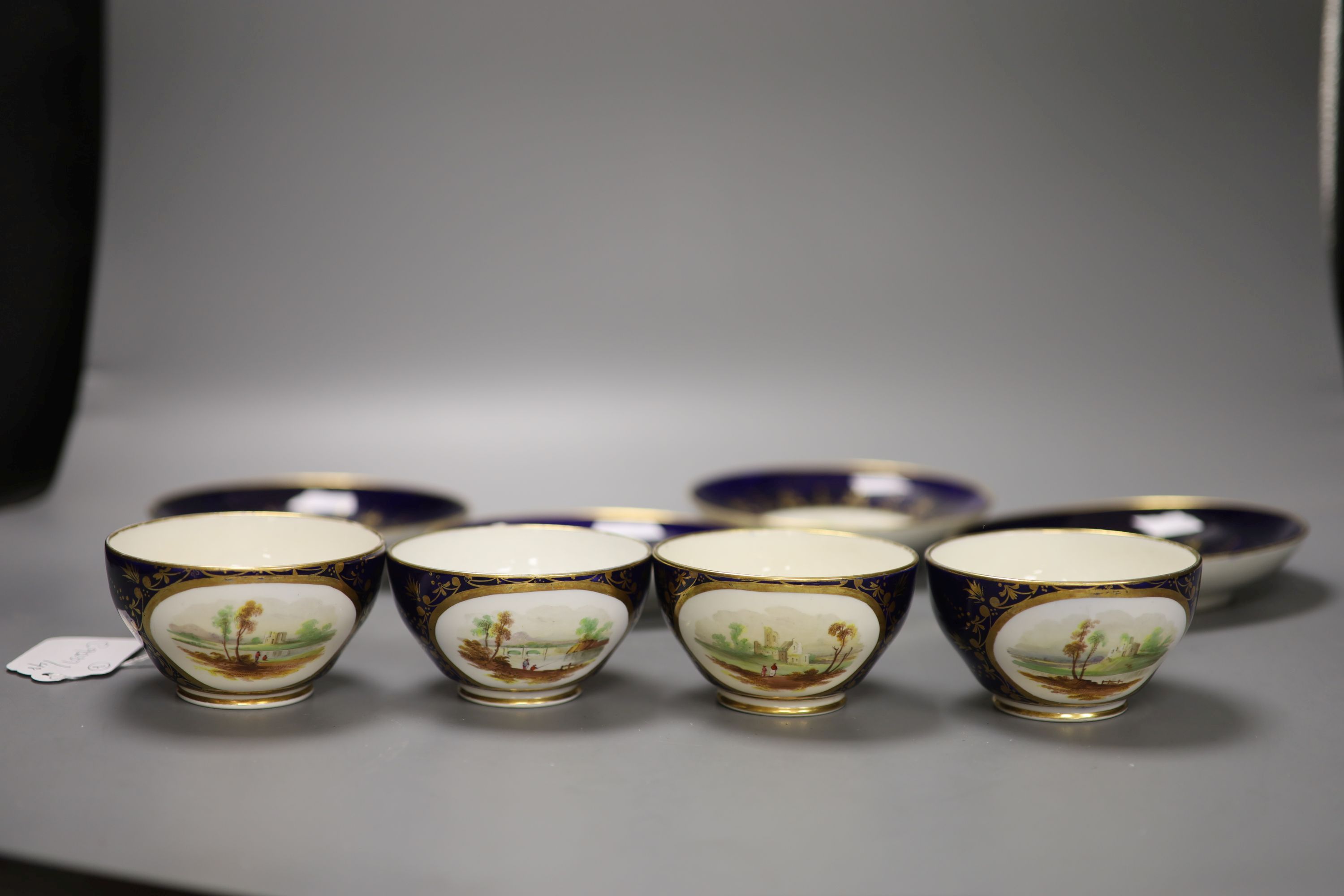 A set of four Derby cups and saucers painted with landscapes on a cobalt blue ground by Henry Lark Pratt, red mark